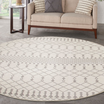 Round beige rug with gray lattice pattern under a beige sofa with striped cushions and a glass-top side table.