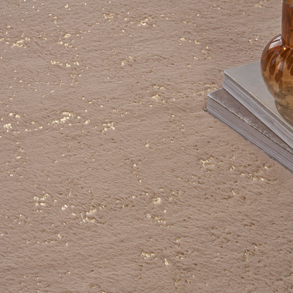 Beige textured rug with gold flecks; amber glass vase atop a stack of magazines.