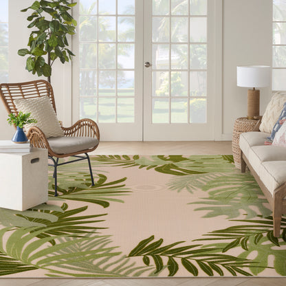 Bright outdoor living area with beige palm-leaf rug, wicker chair, neutral sofa, woven side table, and tropical plants.