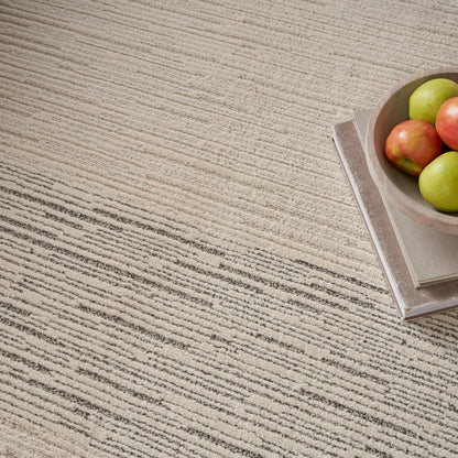Beige striped rug with a small stack of books topped by a wooden bowl of apples on the right.