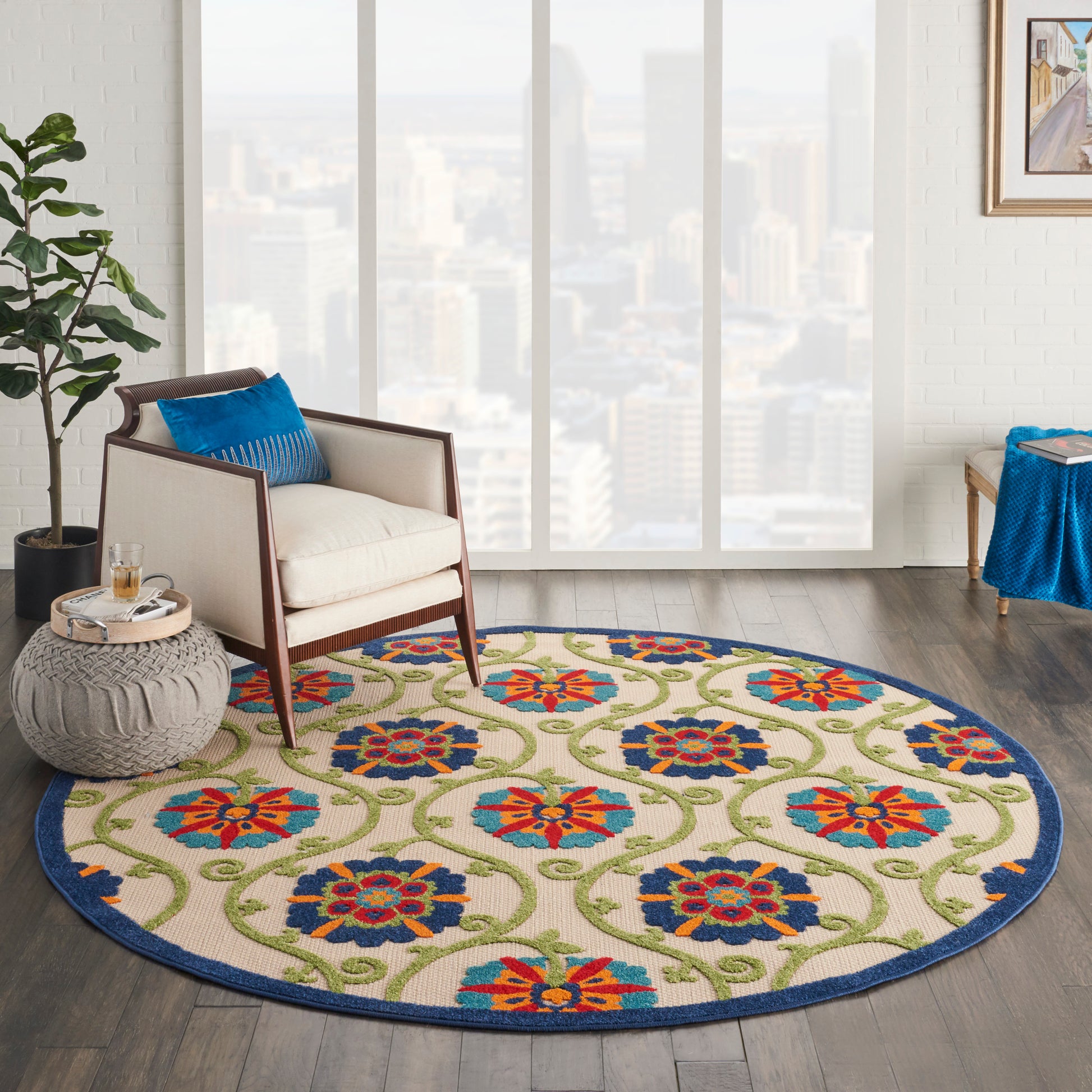 Round boho-style rug with cream base, blue border, and vibrant orange, blue, and green floral medallions; sits in modern living room.
