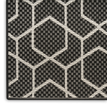 Cream geometric hexagon lattice on black textured weave; close-up of rug-like patterned fabric.