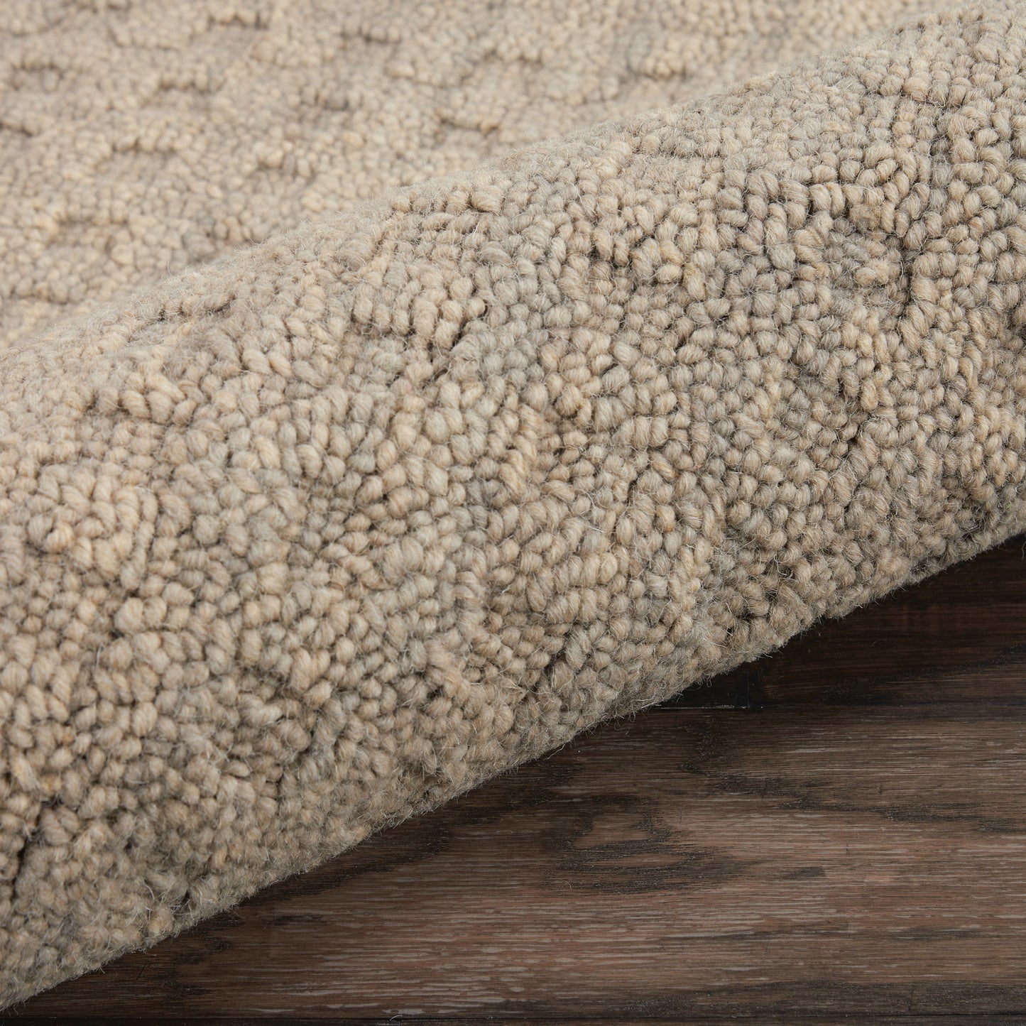 Beige boucle shag rug with chunky textured pile rolled on dark wood floor.
