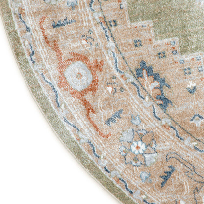 Partial view of round oriental rug: peach-beige field with blue and orange floral motifs and sage-green border.