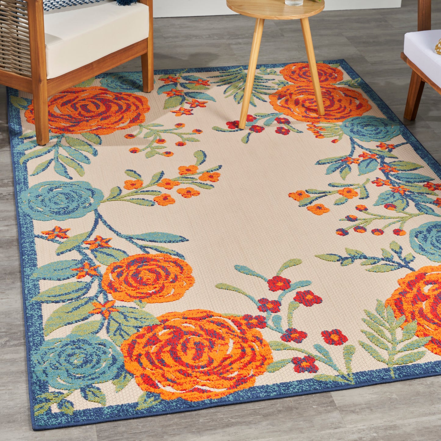 Rectangular outdoor area rug with bold orange and blue floral pattern on cream background, blue border.