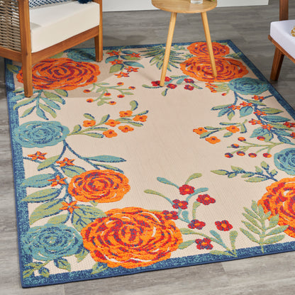 Rectangular outdoor area rug with bold orange and blue floral pattern on cream background, blue border.