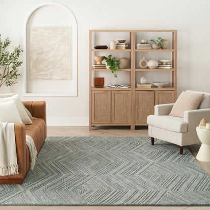 Neutral living room with light wood display cabinets, glass fronts, beige sofa, grey chevron rug, cream armchair, plant.
