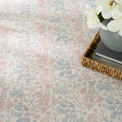 Pastel floral patterned area rug in pink and blue with a woven tray and white flowers.