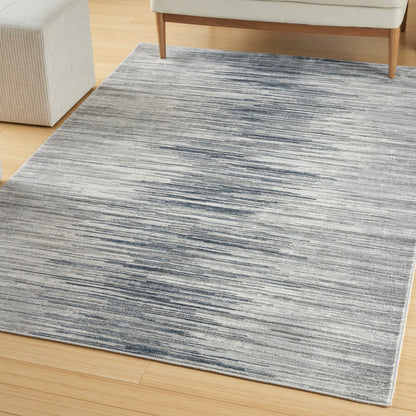 Rectangular gray-blue striped area rug on light wood floor in a living room, with sofa legs visible.