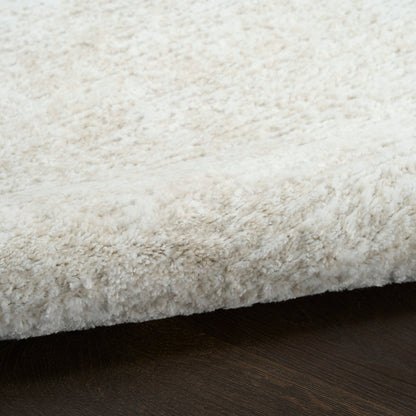 Cream shag rug with fluffy pile and exposed edge on dark wood floor.