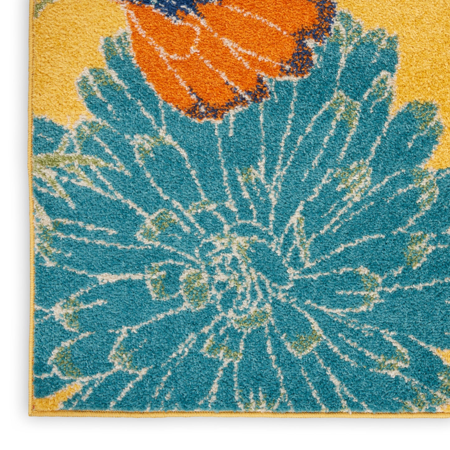 Shaggy runner rug close-up featuring a large blue floral motif with orange accent on a yellow background; wooden edge visible.