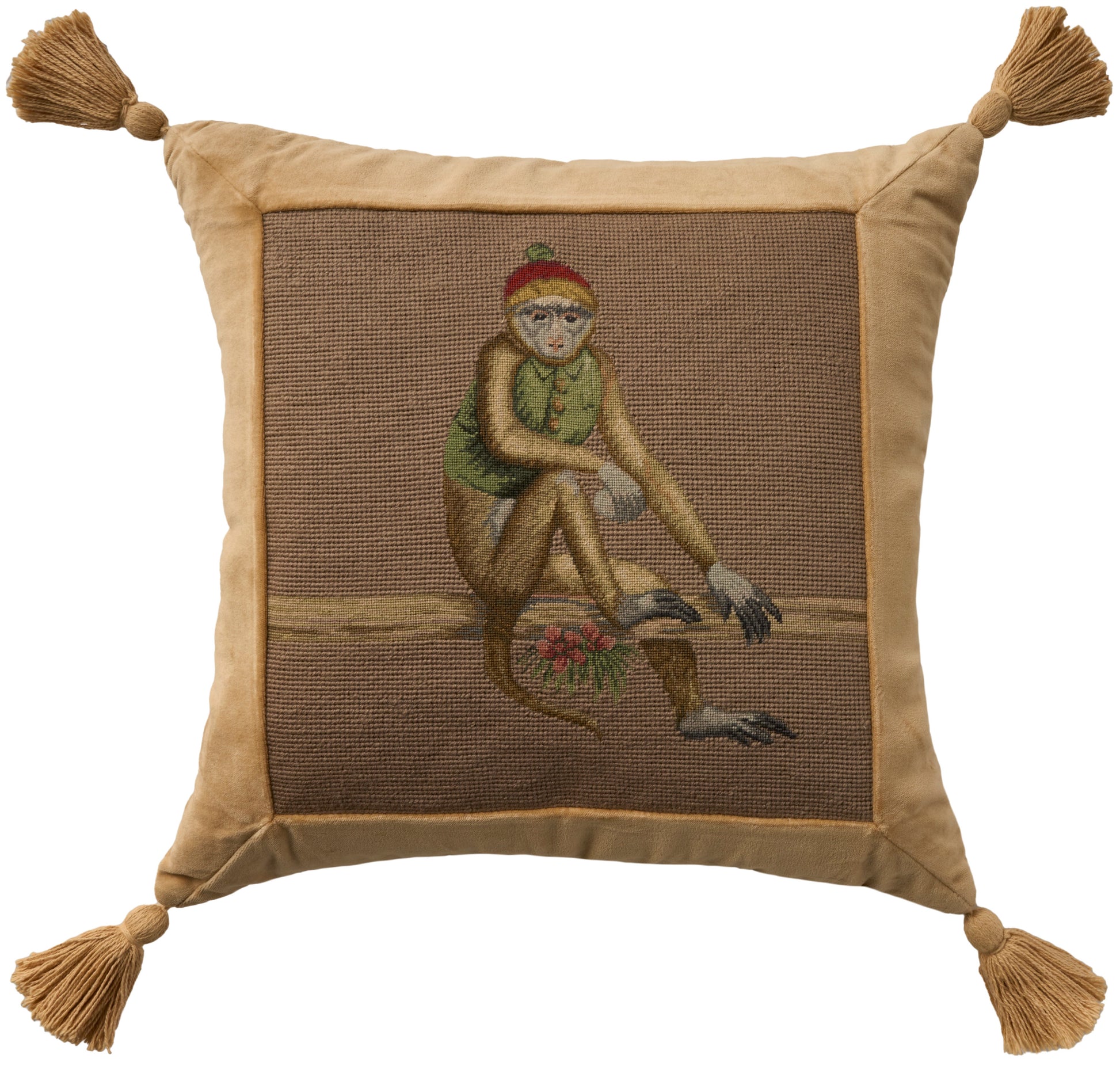 Gold-tan square pillow with tassel corners; embroidered lounging figure on brown panel, wearing green top and red hat.