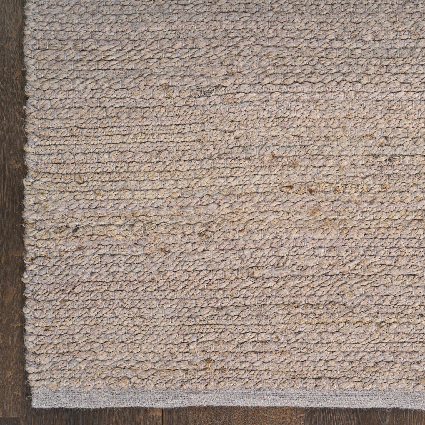 Rectangular beige natural-fiber loop rug with subtle texture on dark wood floor.