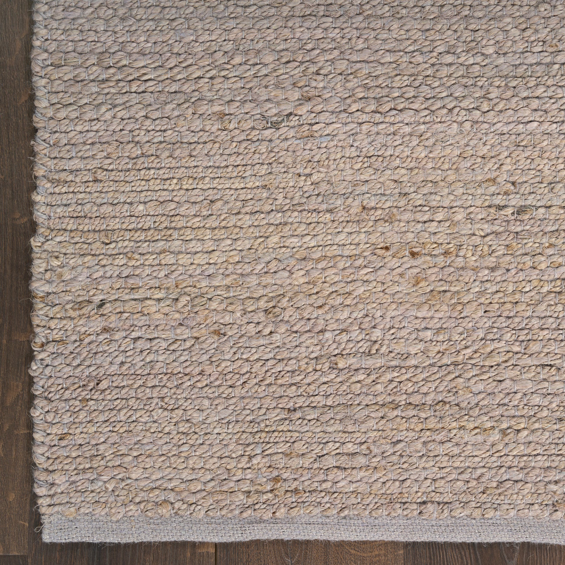Rectangular beige natural-fiber loop rug with subtle texture on dark wood floor.