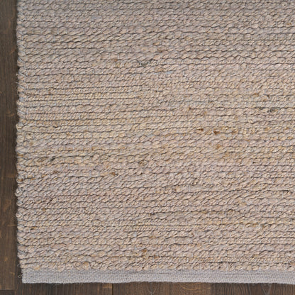 Rectangular beige natural-fiber loop rug with subtle texture on dark wood floor.
