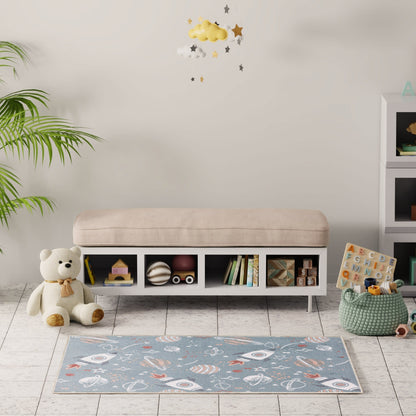 Cozy playroom with a beige cushioned bench, white cubby storage, teddy bear, blue space-pattern rug, and a plant.