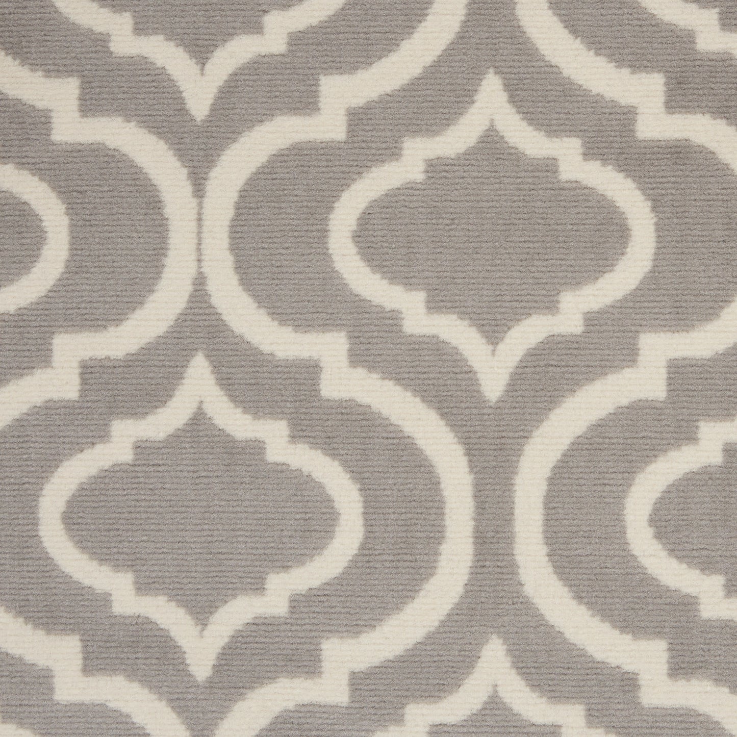 Grey rug with white Moroccan quatrefoil lattice pattern; woven textile for contemporary decor.