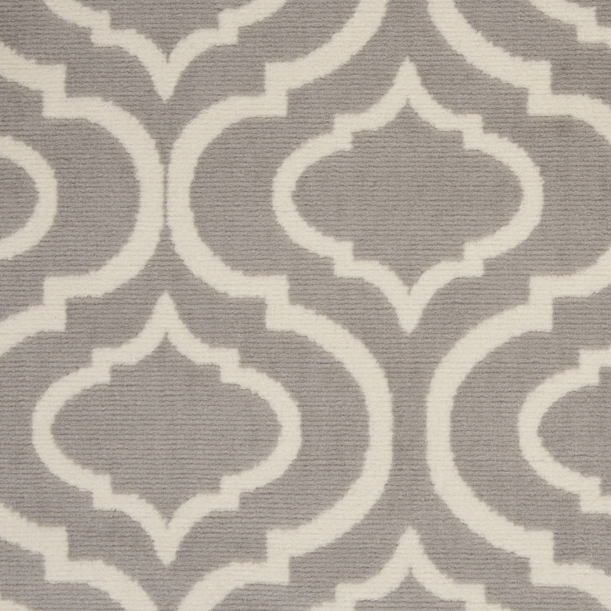 Grey rug with white Moroccan quatrefoil lattice pattern; woven textile for contemporary decor.