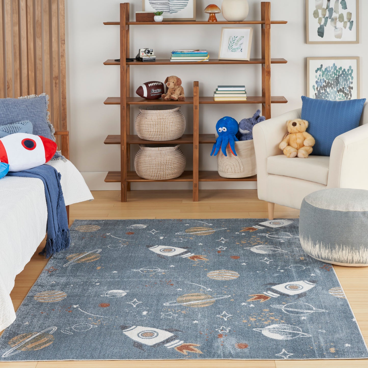Blue space-themed area rug with rockets and planets in a cozy kid-friendly living room with a wooden bookshelf.