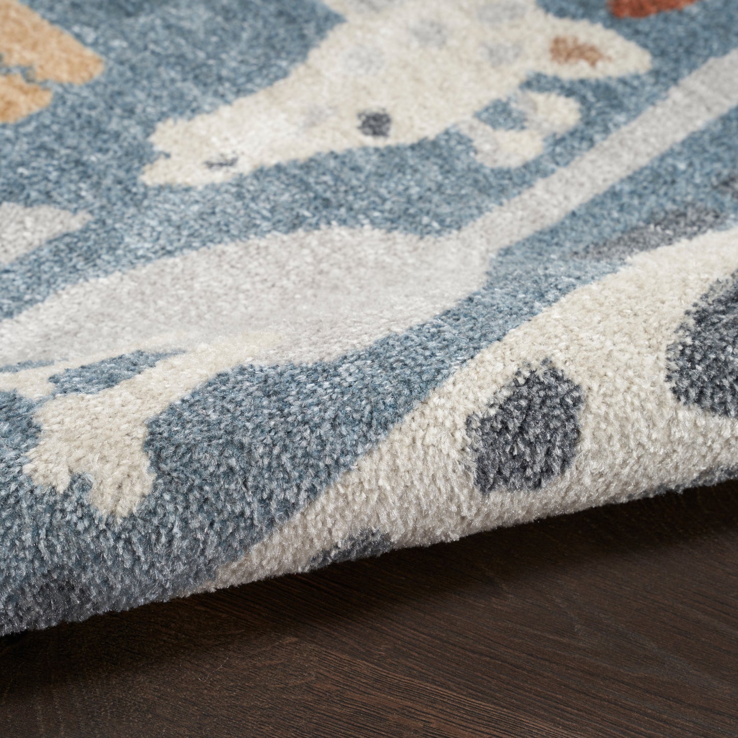 Close-up of blue and cream plush round area rug with abstract motif on dark wood floor.