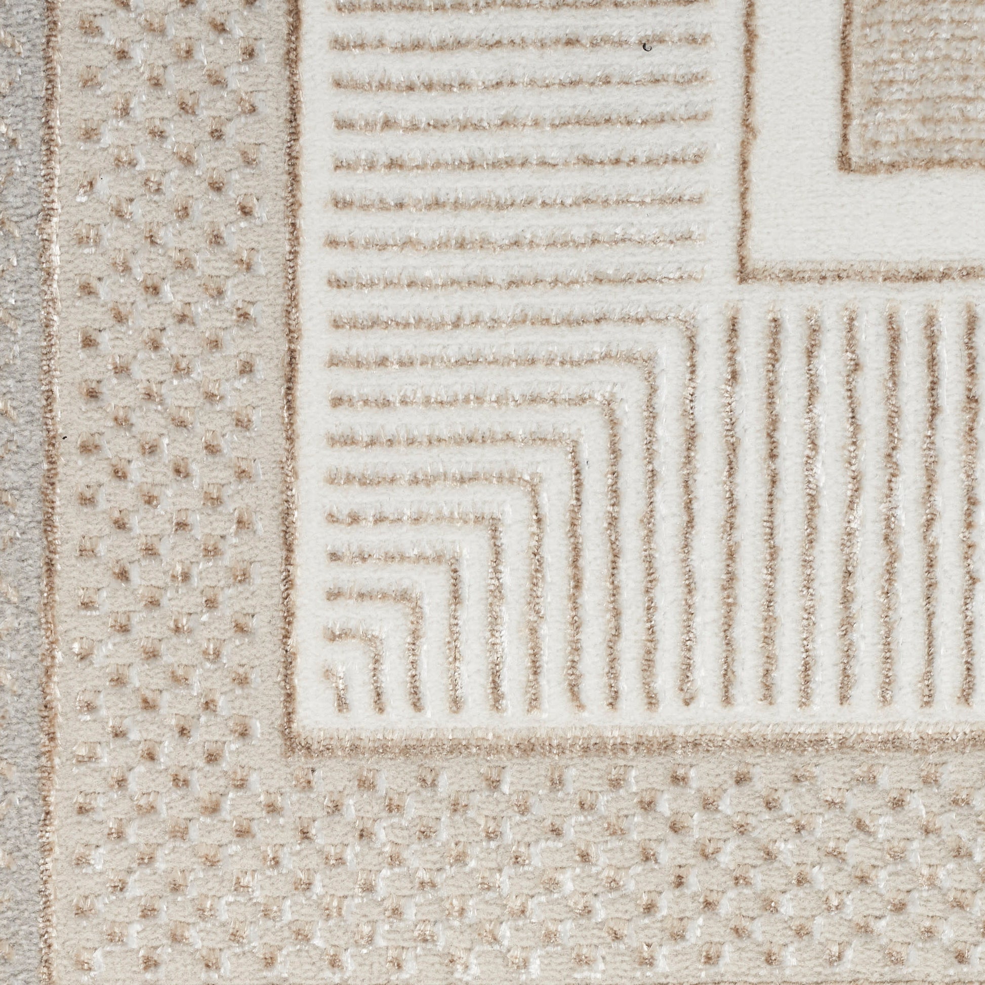 Beige textured rug with geometric borders and raised linear patterns plus dotted sections in cream.