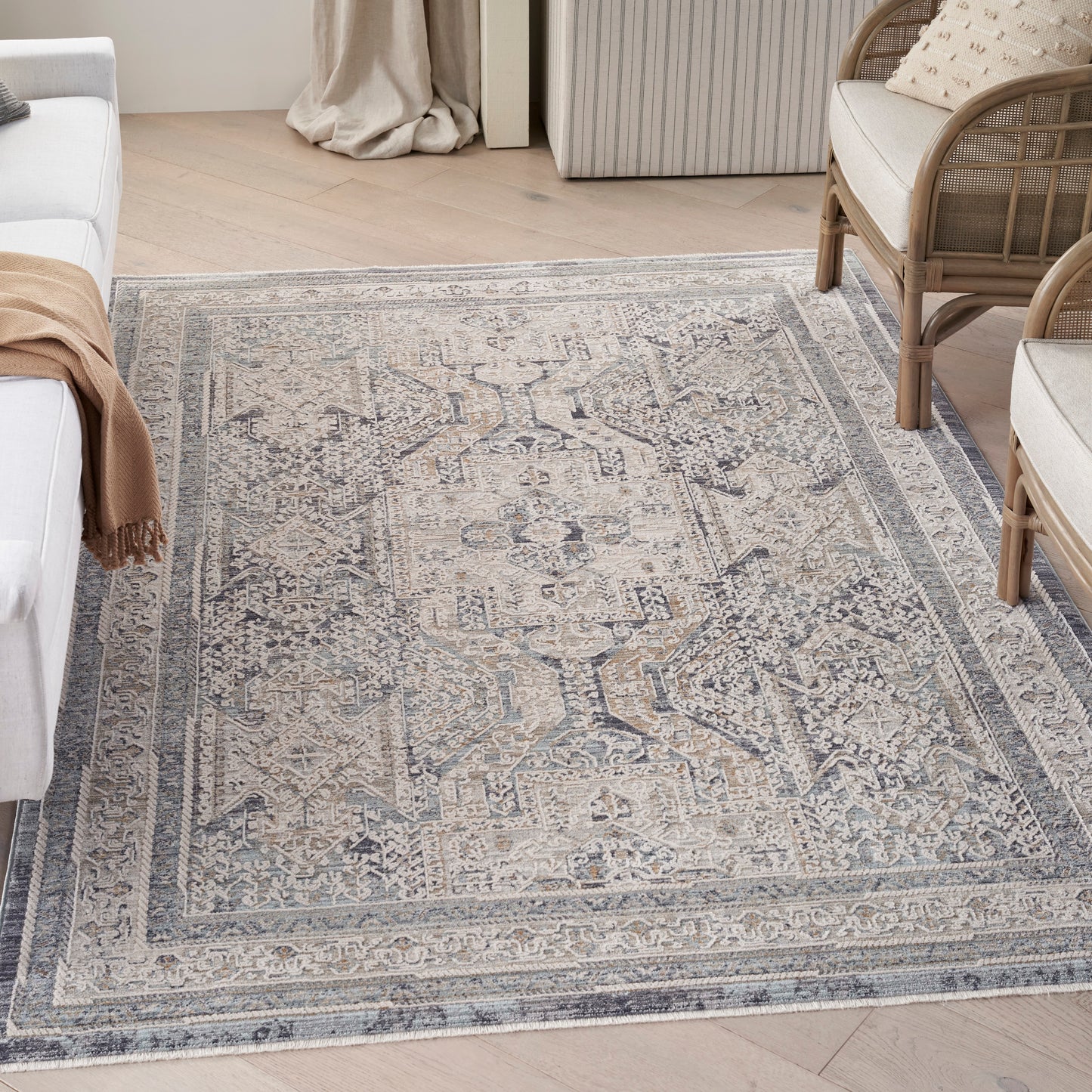 Muted blue-gray oriental rug with ivory distressed medallion pattern and bordered edges in a light living room.
