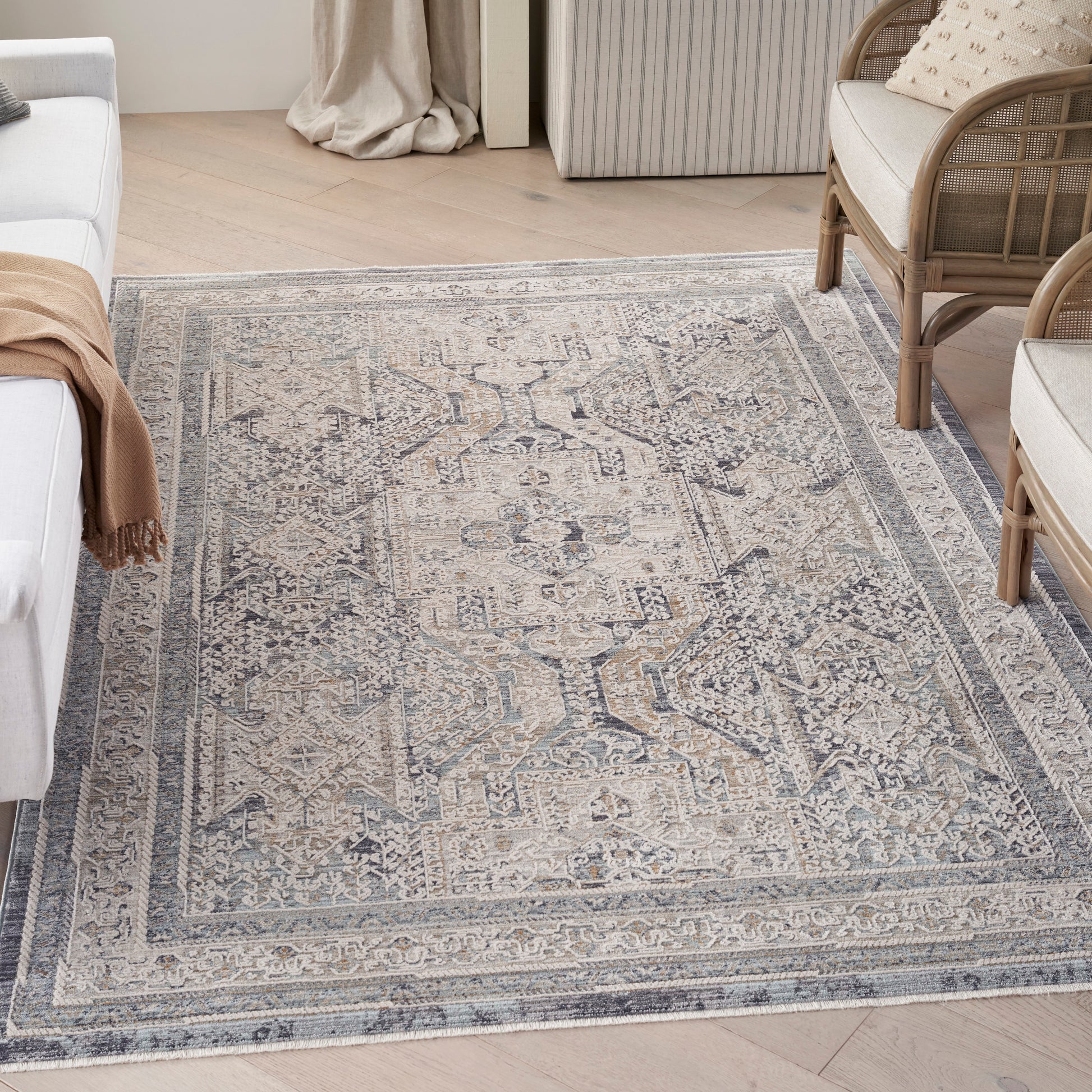 Muted blue-gray oriental rug with ivory distressed medallion pattern and bordered edges in a light living room.