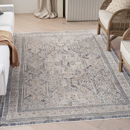 Muted blue-gray oriental rug with ivory distressed medallion pattern and bordered edges in a light living room.
