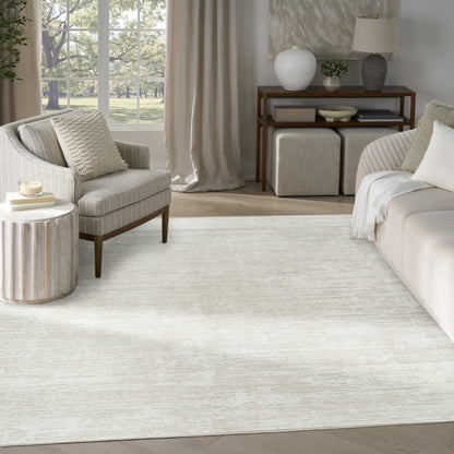 Soft, textured cream rectangular area rug in a neutral living room with beige sofa, armchair, and wooden console.