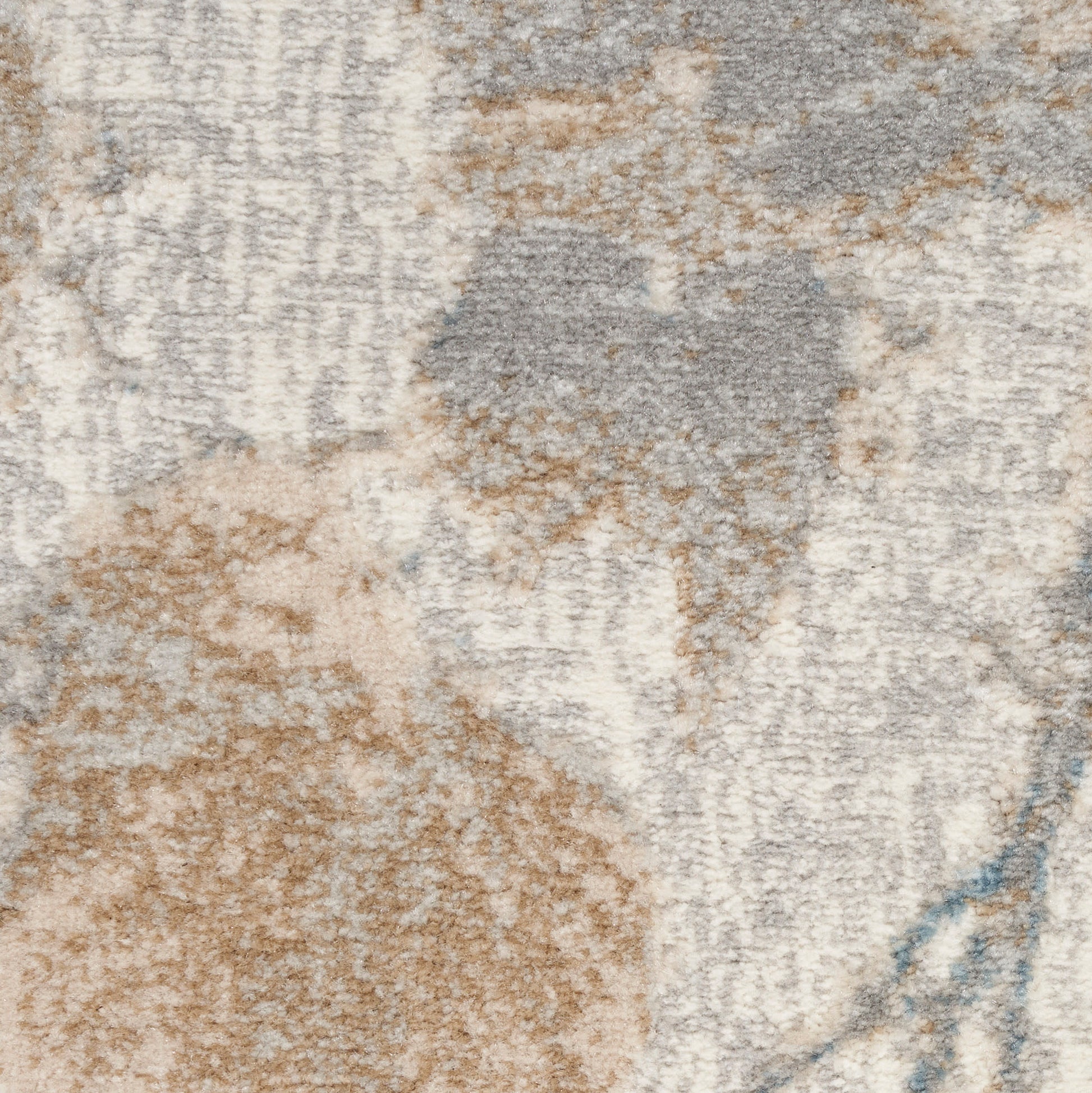 Close-up of a textured abstract area rug in beige, taupe, gray and pale blue with a soft plush pile.