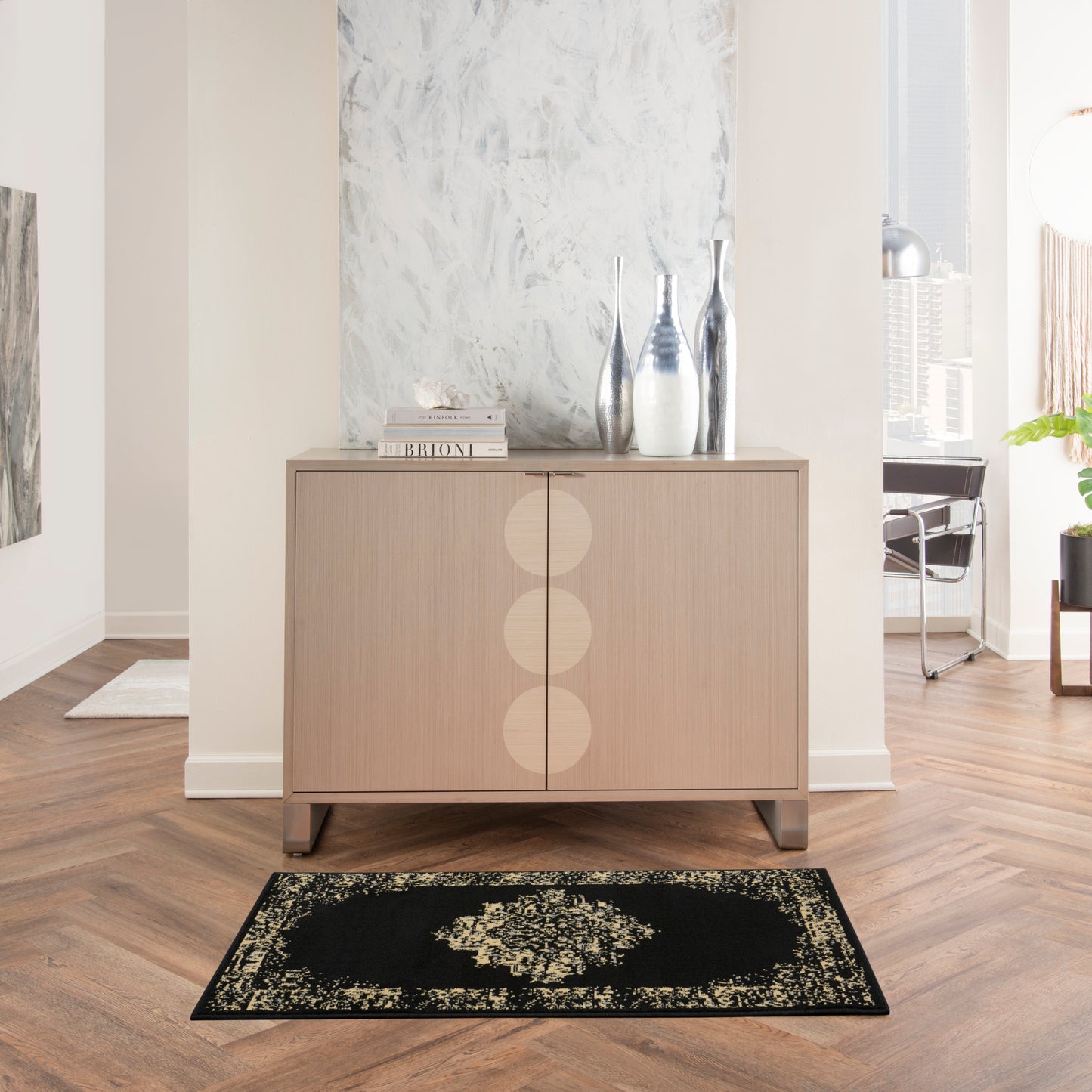 Light oak sideboard with circular inset doors, metallic vases on top, in a bright modern living room with a black beige rug.