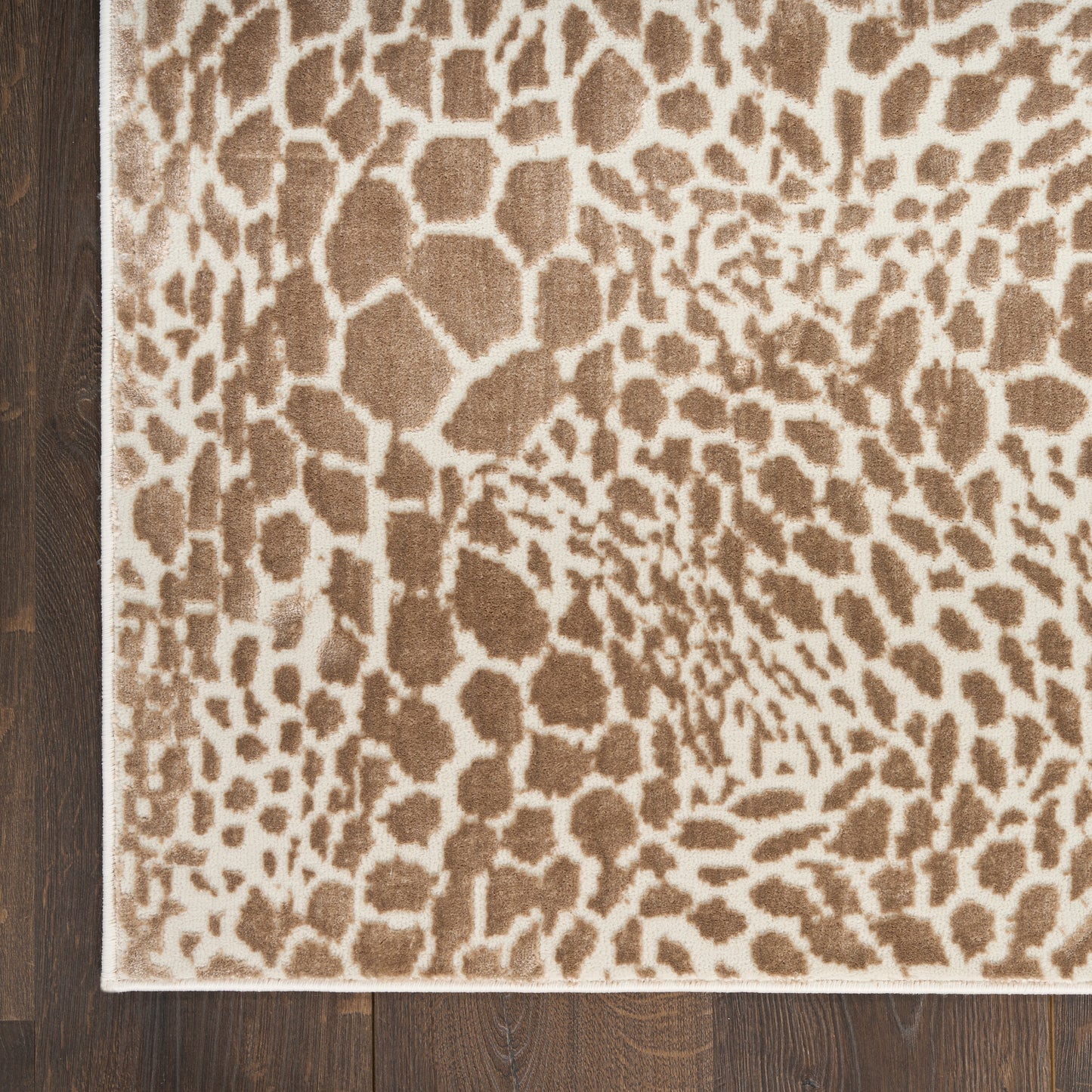 Beige leopard-print area rug with brown spots and light border on dark wood floor.