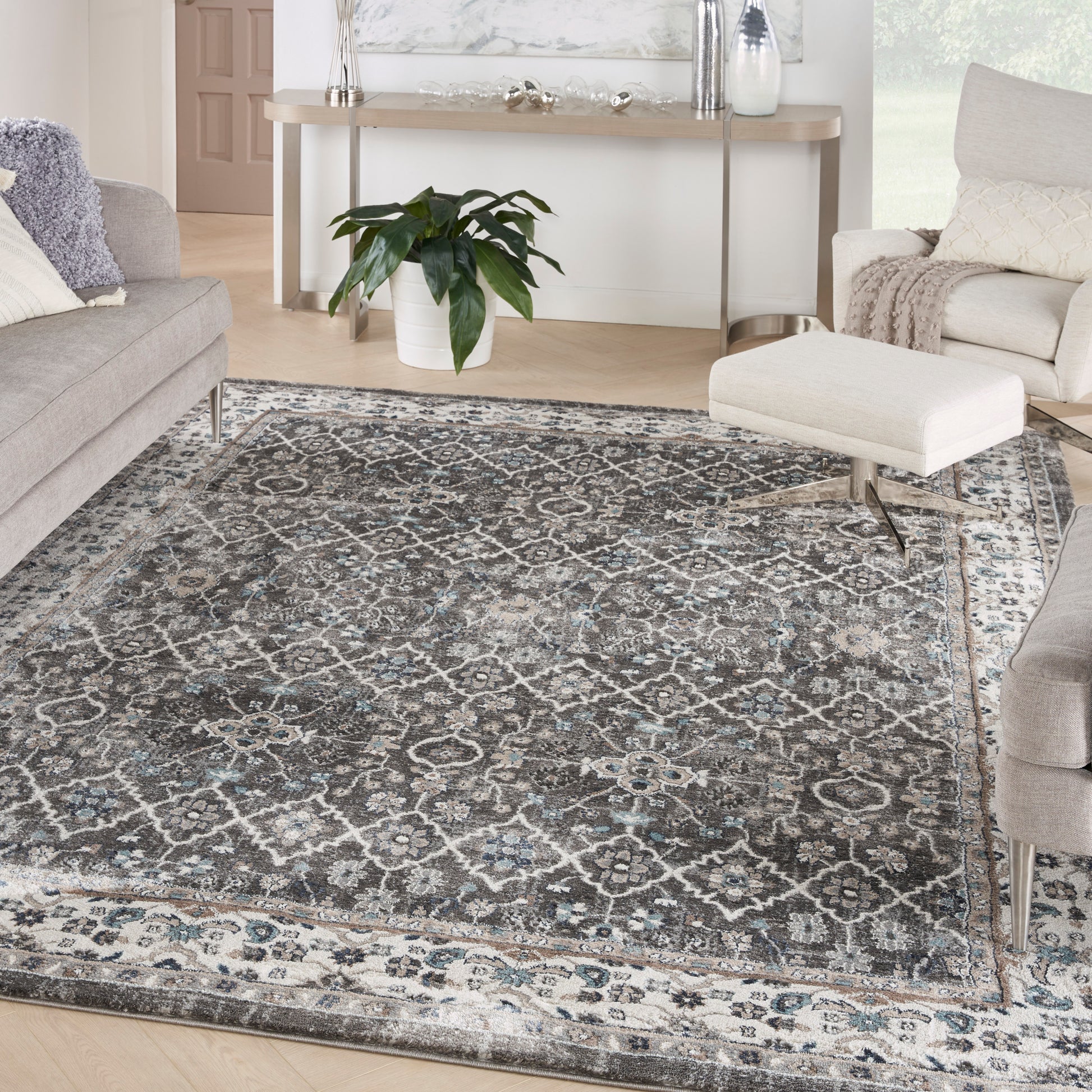 Rectangular gray-blue vintage oriental area rug with ivory pattern in a modern living room with gray sofas & white ottoman