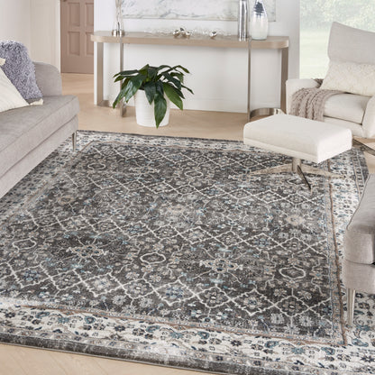 Rectangular gray-blue vintage oriental area rug with ivory pattern in a modern living room with gray sofas & white ottoman