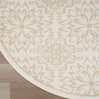 Round rug with cream background and beige damask floral pattern, woven texture on wood floor.