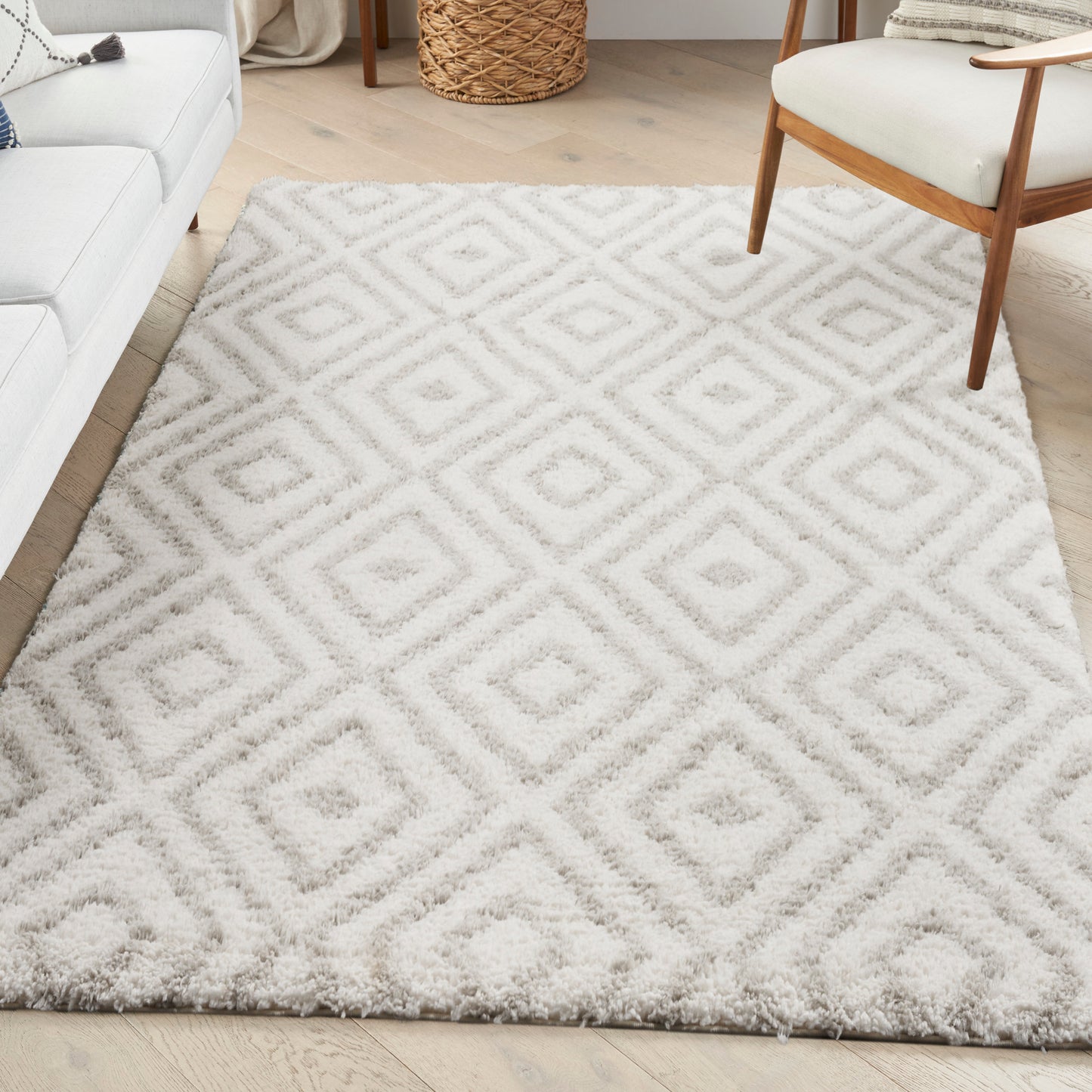 Cream shag rug with pale gray geometric diamond pattern in a cozy living room beside a white sofa and mid-century chair.