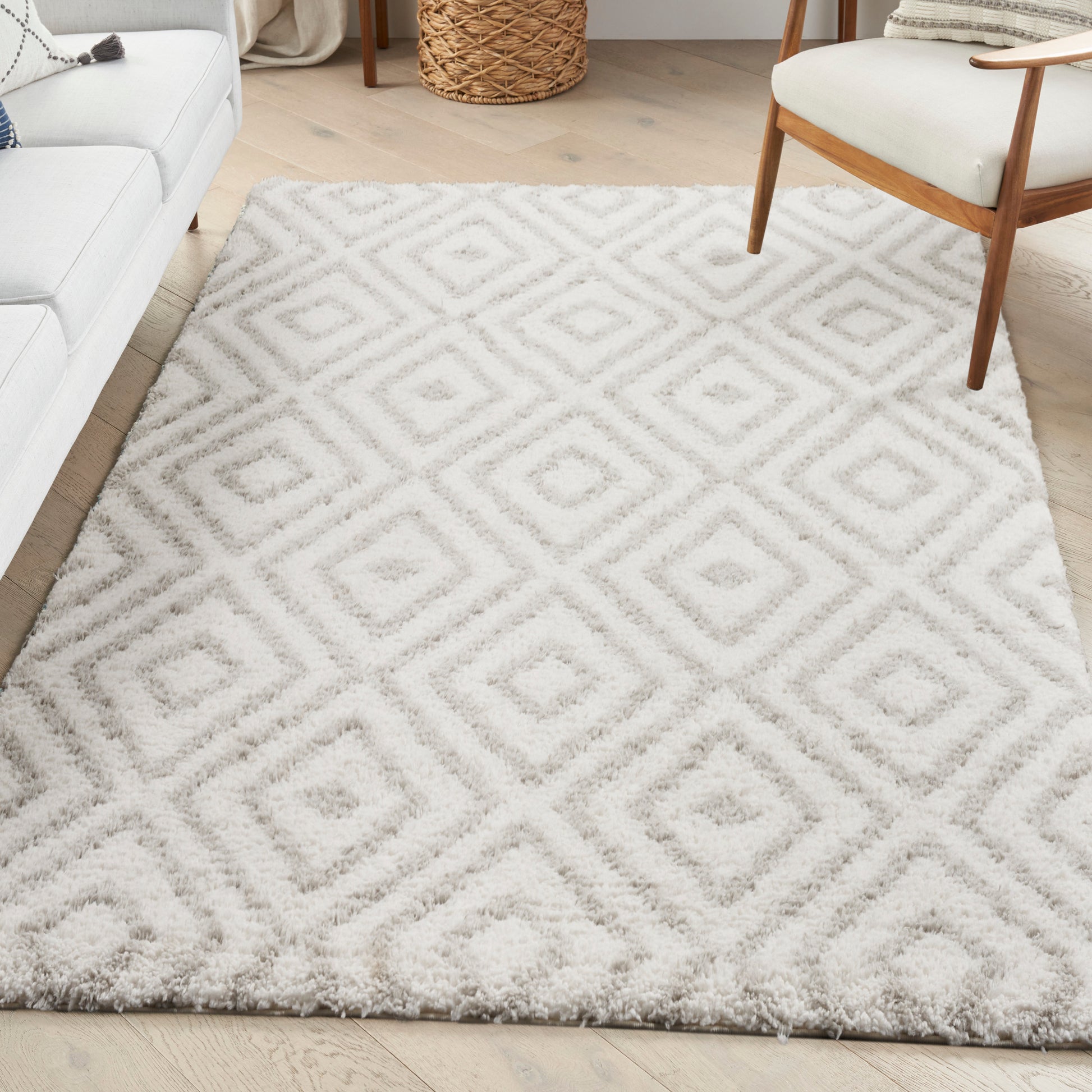 Cream shag rug with pale gray geometric diamond pattern in a cozy living room beside a white sofa and mid-century chair.