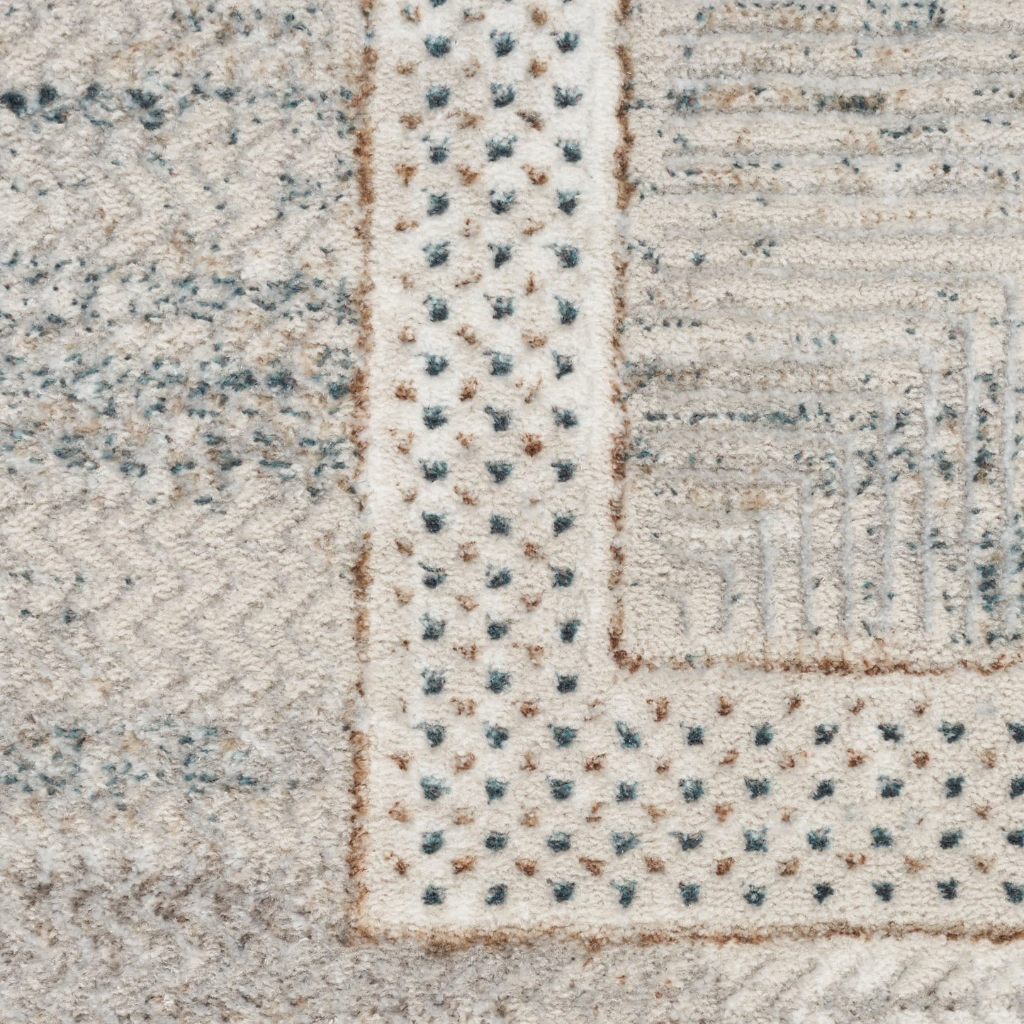 Neutral patchwork area rug in cream, gray and beige with dotted border and textured pile.