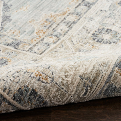 Close-up of a blue-gray and cream oriental rug with orange accents, folded over on a dark wooden floor.