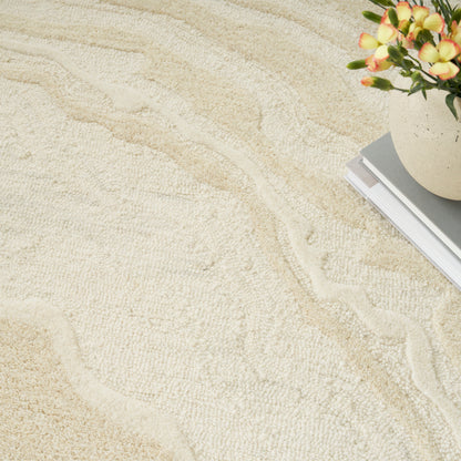 Beige textured rug with wavy patterns, plus a ceramic pot of orange flowers and a stack of books in the corner.