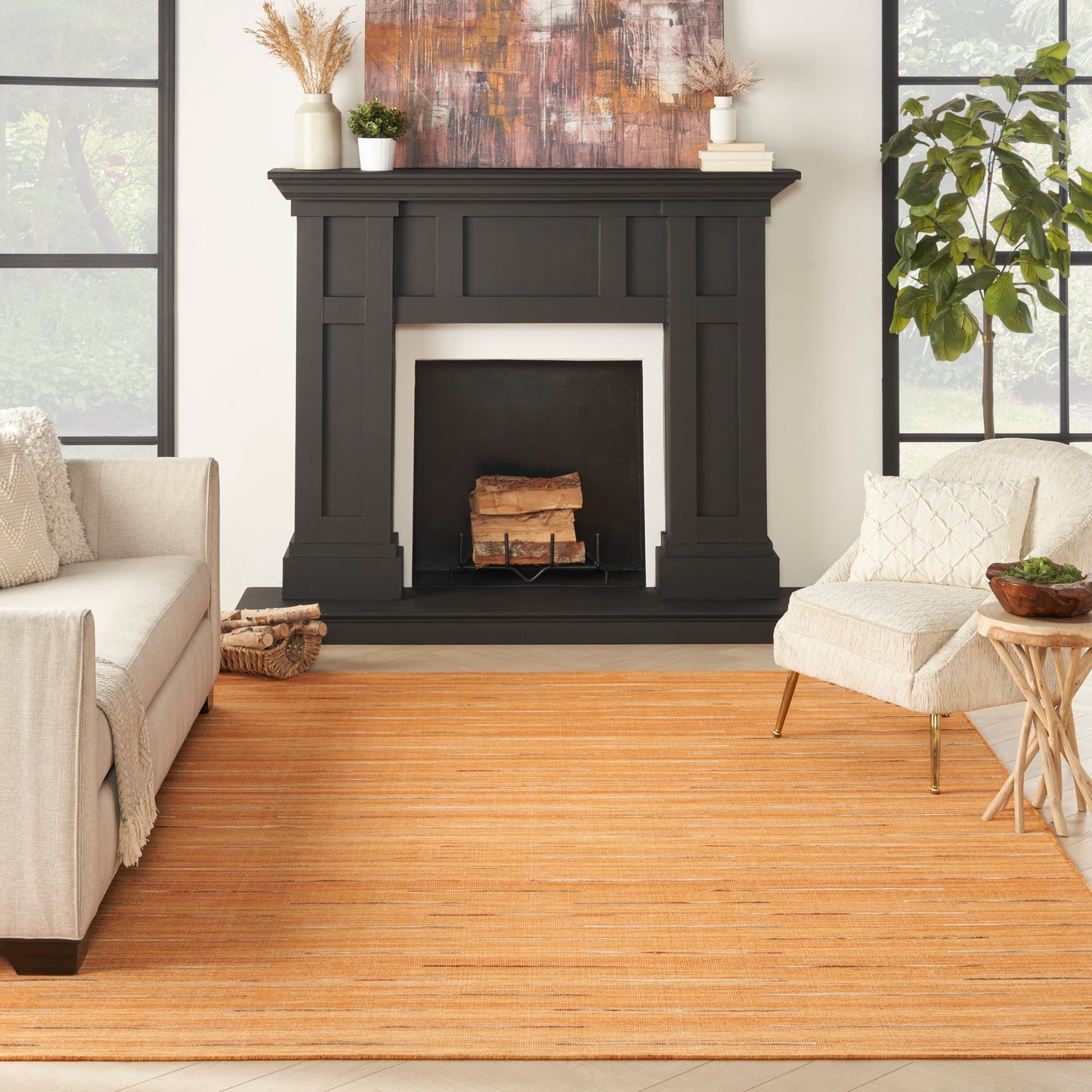 Living room with a black mantel fireplace, warm orange striped rug, beige sofas, green plants, and a large abstract painting.