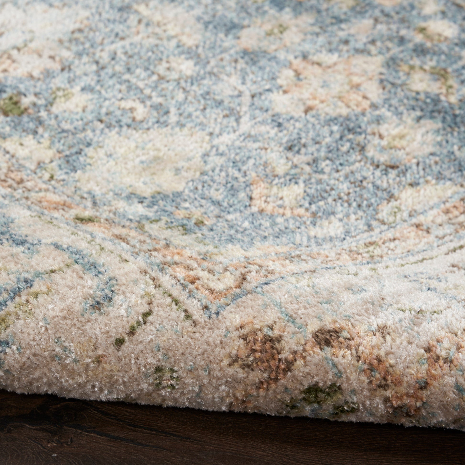 Close-up of a plush blue and cream patterned area rug with beige and green accents.