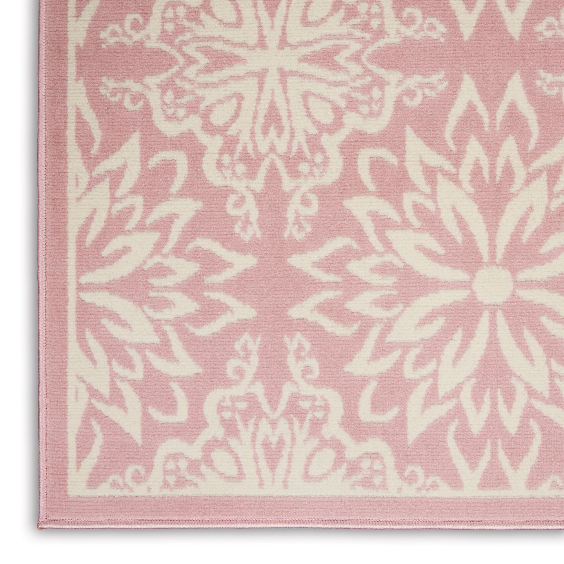 Pink rug with white ornate floral/mandala motifs; rectangular woven textile with light pink border.