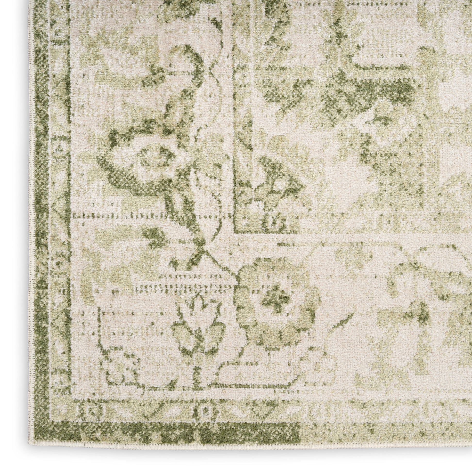 Corner of a beige woven rug with sage green vintage floral pattern and decorative border