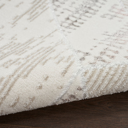 Cream and beige abstract-pattern area rug with soft plush pile on dark wood floor.