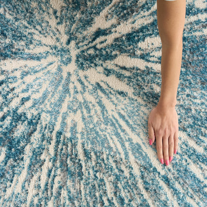 Arm with pink nail polish resting on a blue and cream tie-dye rug.