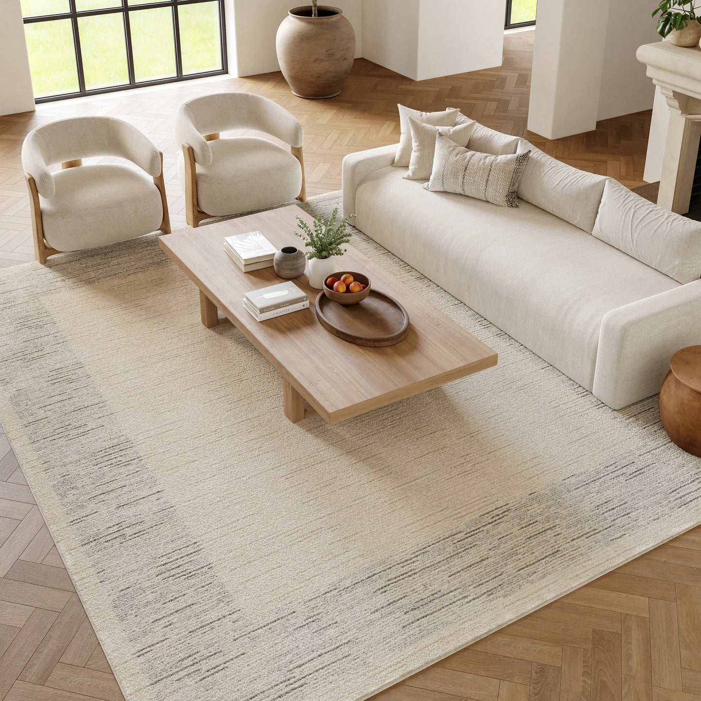 Neutral living room with cream sofa, two armchairs, wooden coffee table, beige patterned rug.