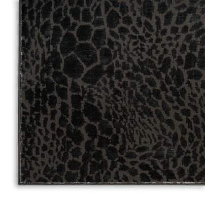 Close-up of black faux leather with embossed leopard print texture and a visible edge seam.