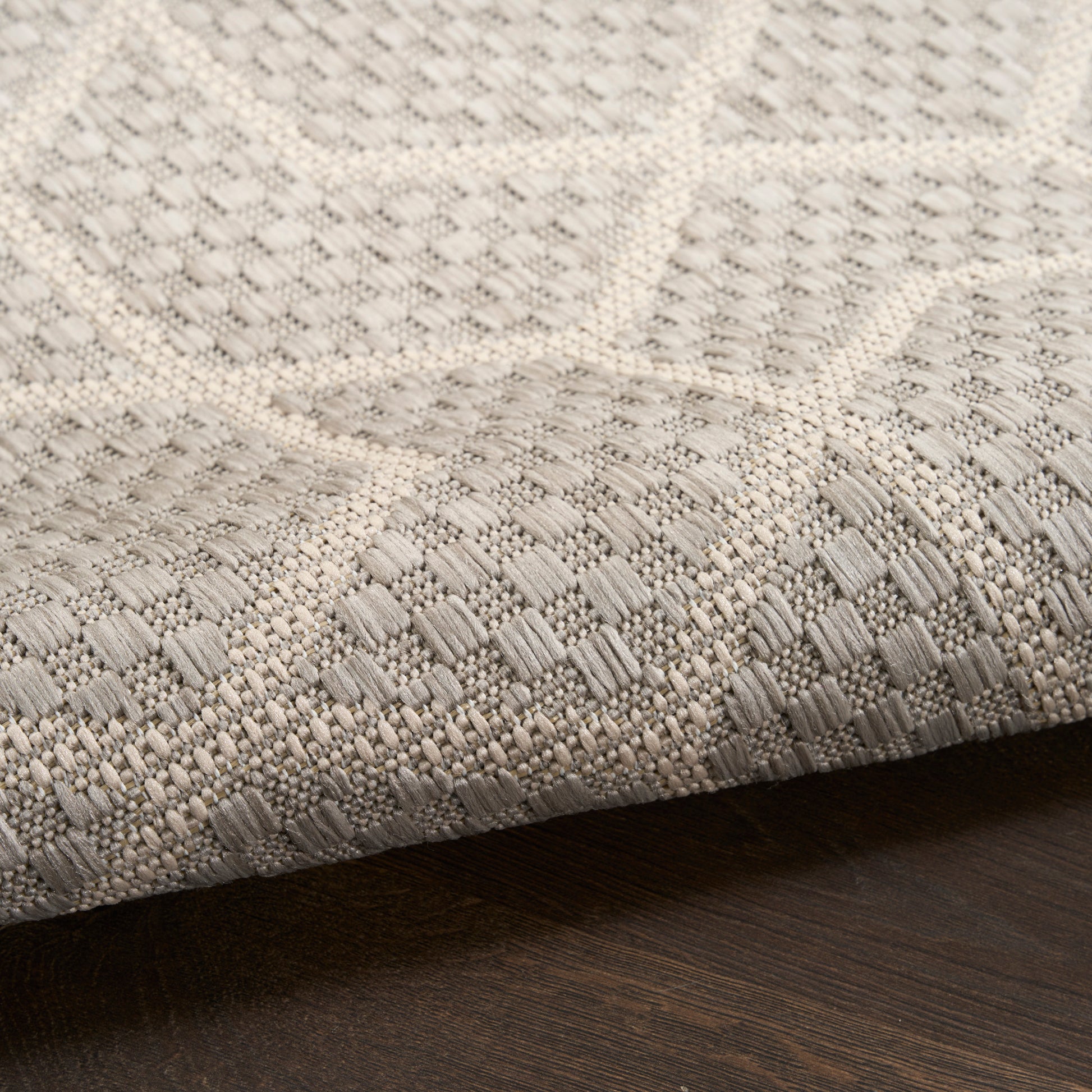 Neutral woven runner rug with geometric square pattern in cream and gray on dark wood floor
