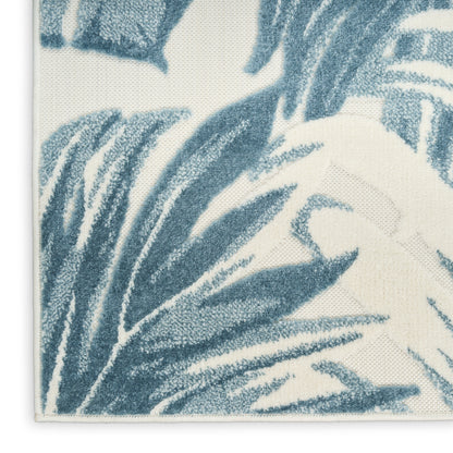 Close-up of a cream rug featuring blue palm leaf print and textured weave.